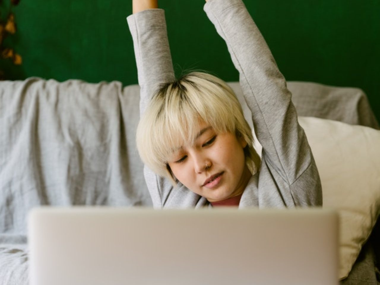 unemotional-woman-stretching-arms-while-working-on-laptop-4132301/