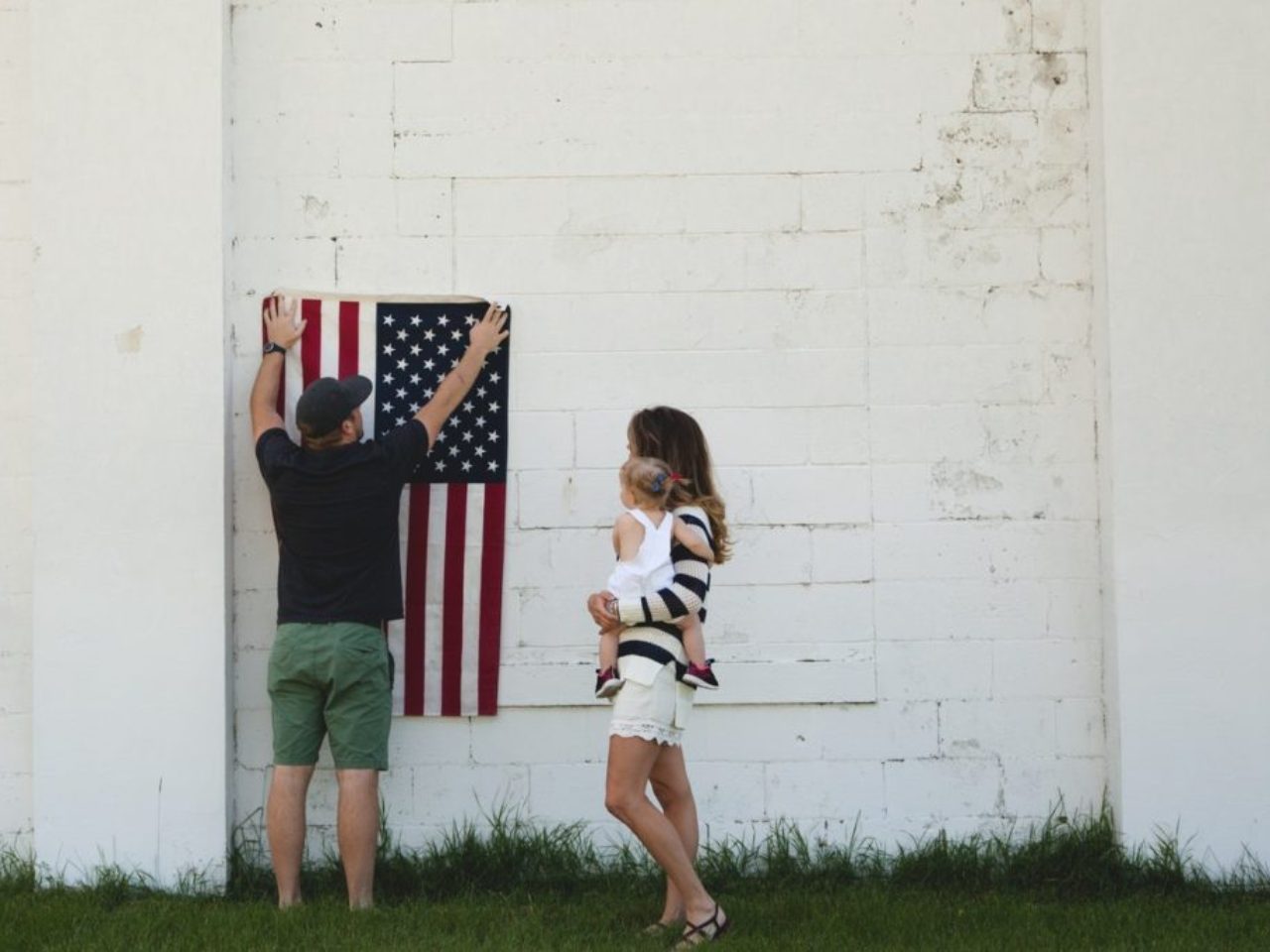 man-holding-u-s-us-flag-next-to=woman-and-child